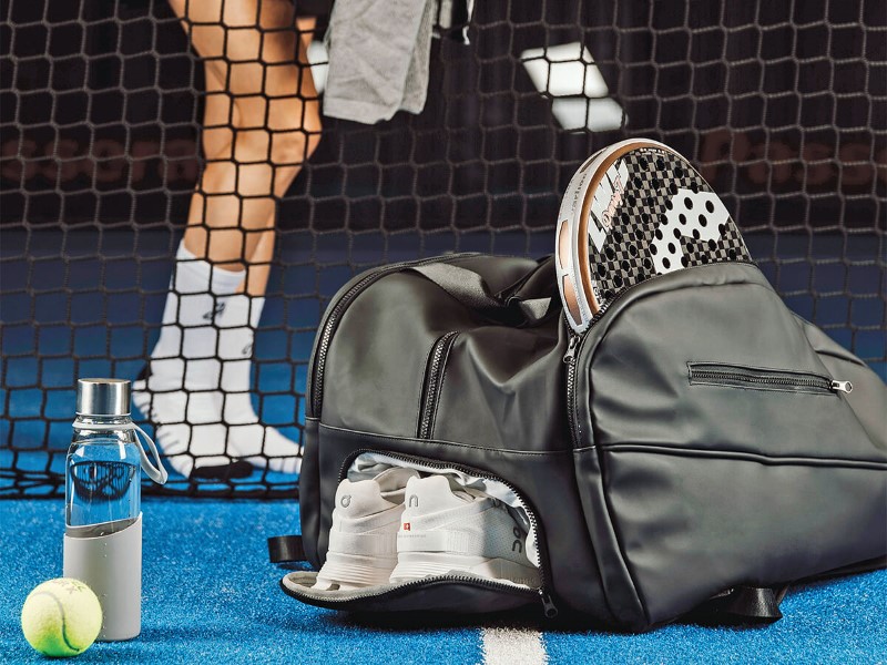 Bolsa de deporte elegante en pista de pádel con raqueta y zapatillas